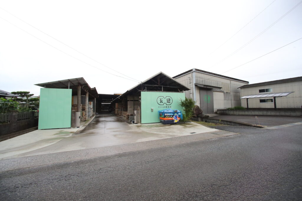 伊予市下三谷の自社倉庫・加工場。緑の「玉建」ロゴが目印です
